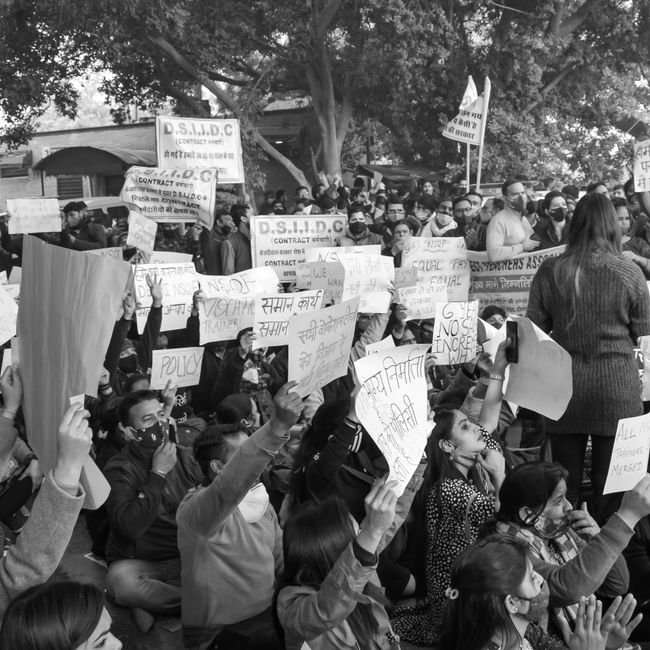 A grayscale image of protesters holding signs and placards during a demonstration.