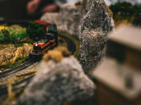 A miniature train navigates through a detailed model landscape, capturing realistic features.