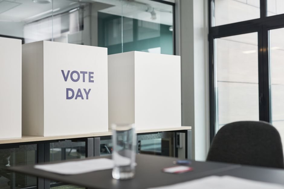 Delhi Electoral Roll Revision Sees Over 62,000 New Inclusion Applications in 15 Days A modern office with voting booths labeled 'Vote Day' indicating election activity.