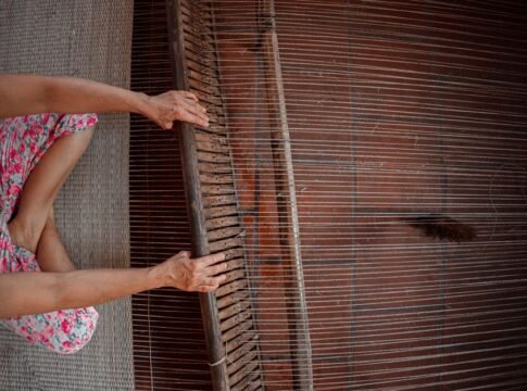 A person weaving fabric on a traditional wooden loom, showcasing intricate craftsmanship. A person weaving fabric on a traditional wooden loom, showcasing intricate craftsmanship.