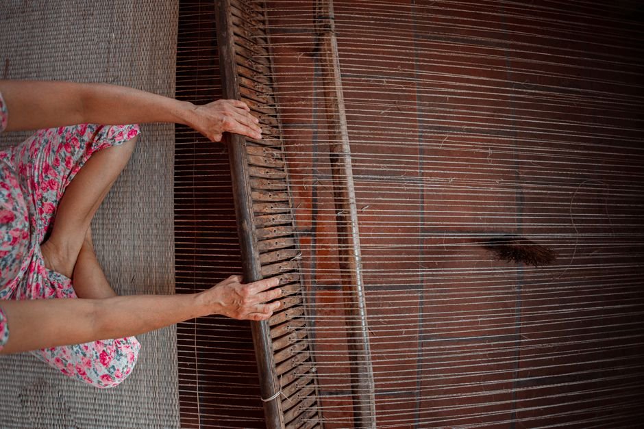 Tamil Nadu Government Boosts Handloom Weaver Wages, Establishes Knitwear Board A person weaving fabric on a traditional wooden loom, showcasing intricate craftsmanship.