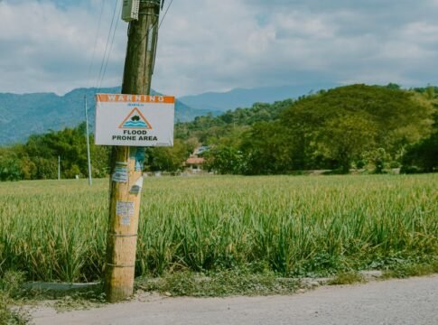 A rural scene with a flood warning sign against a mountainous backdrop. A rural scene with a flood warning sign against a mountainous backdrop.