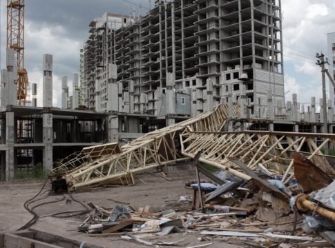 An urban construction site featuring a collapsed crane and unfinished buildings under cloudy skies.