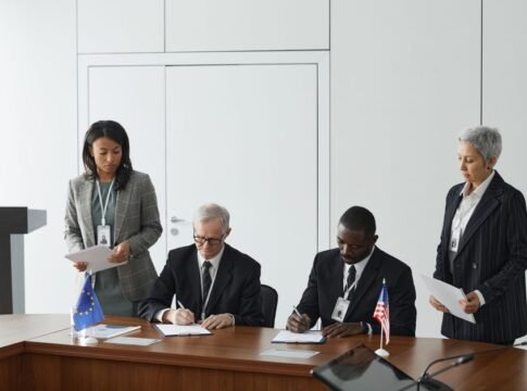 Business leaders signing a significant agreement in a conference room setting. Business leaders signing a significant agreement in a conference room setting.