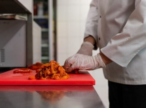 Chef chopping vegetables on a red cutting board in a professional kitchen. Chef chopping vegetables on a red cutting board in a professional kitchen.