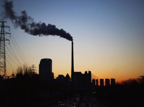 Dramatic sunset silhouette of an industrial smokestack with pollution in the urban skyline. Dramatic sunset silhouette of an industrial smokestack with pollution in the urban skyline.