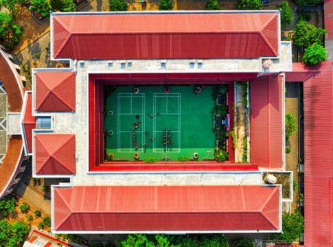Drone view of a school courtyard with a green tennis court in Jakarta, Indonesia.