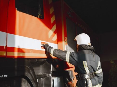 Firefighter in safety gear working with a fire truck outdoors during the day. Firefighter in safety gear working with a fire truck outdoors during the day.