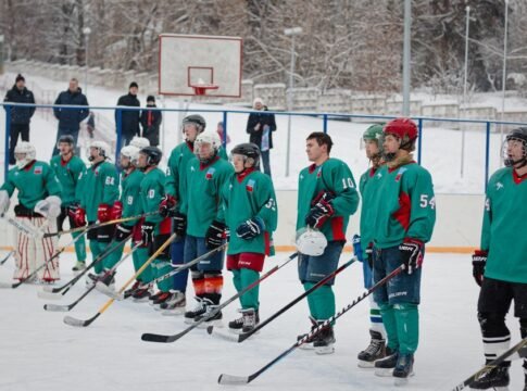 Group of male ice hockey players standing in a row during a winter match outdoors.