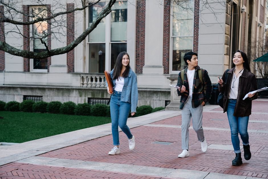 Karnataka: VTU Mandates Interaction Time for Engineering College Principals Group of young students walking on campus sidewalk on a bright day, showcasing casual university life.