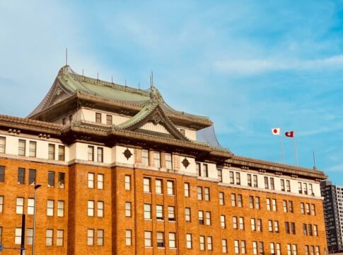 Historic government building facade in Nagoya showcasing imperial crown style architecture under a bright blue sky.