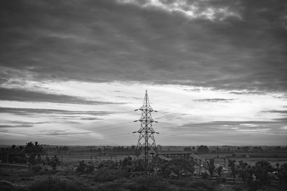 Monochrome rural landscape featuring transmission tower and clouds in Nanguneri, India.