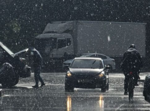 Moody urban street scene in heavy rain with cars and pedestrians.
