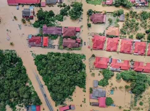 Overhead view of colorful roofs of residential buildings and lush green trees in flooded small village