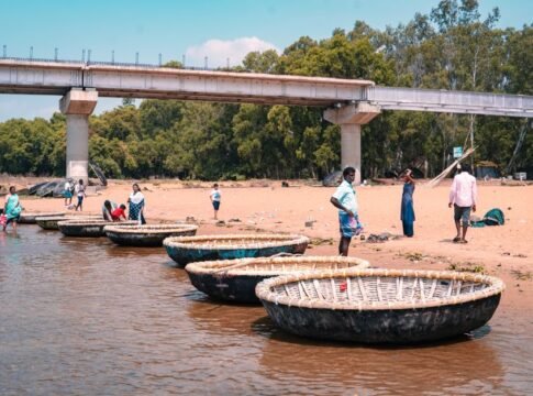 People enjoy a serene day by coracle boats on a sandy riverbank in Mysuru, India. People enjoy a serene day by coracle boats on a sandy riverbank in Mysuru, India.