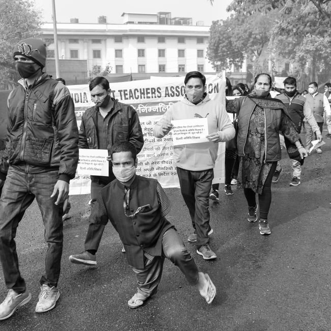 Himachal Pradesh University Teachers Urge CM to Protect Varsity Autonomy Protesters march for teachers' rights, holding banners in an urban setting.
