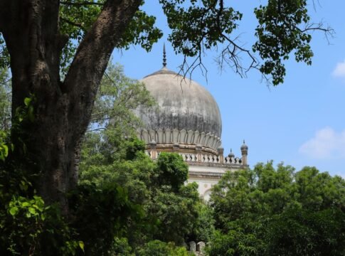 Qutb Shahi tomb framed by dense trees on a bright summer day. Qutb Shahi tomb framed by dense trees on a bright summer day.