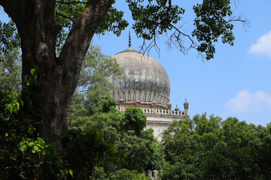 Jammu and Kashmir: MANUU Officials Discuss Madrasa Equivalency with Ramban Representatives Qutb Shahi tomb framed by dense trees on a bright summer day.
