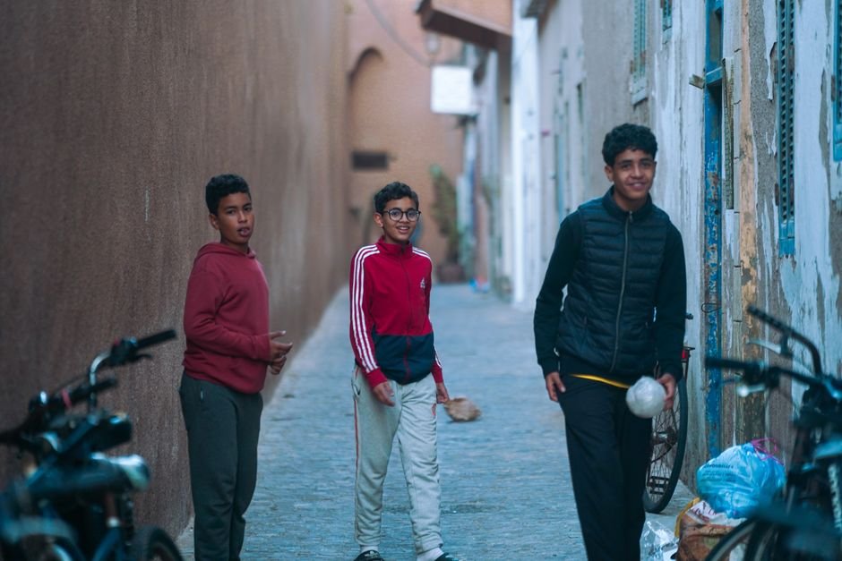Moroccan Youth Disillusionment Casts Shadow Over National Elections Amidst Economic Woes Three teenagers walk through a narrow alley in the Medina of Essaouira, Morocco.