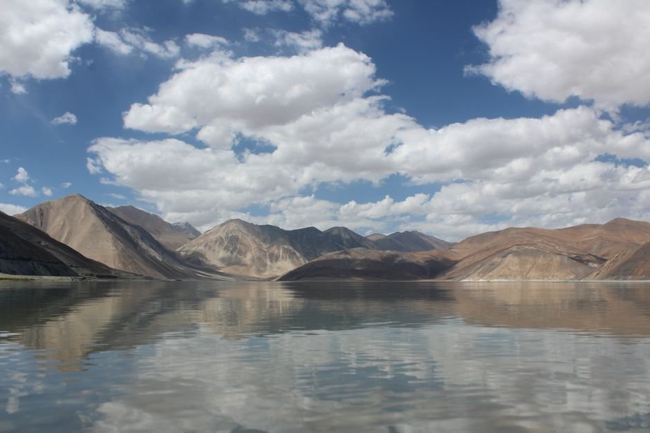 Ladakh: Four Him Sarovar Ponds Filled with Glacier Meltwater in Leh Tranquil mountain lake reflecting a clear blue sky with clouds.