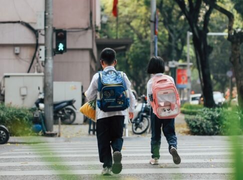 Two children with backpacks crossing a street at a pedestrian crossing. Two children with backpacks crossing a street at a pedestrian crossing.