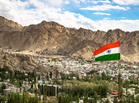 View of Leh city with the Indian flag against majestic mountains under a vibrant sky. View of Leh city with the Indian flag against majestic mountains under a vibrant sky.