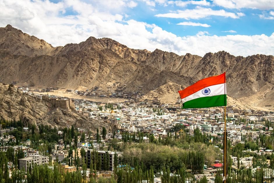 Ladakh High Court Bench Regulation Comes Into Effect View of Leh city with the Indian flag against majestic mountains under a vibrant sky.
