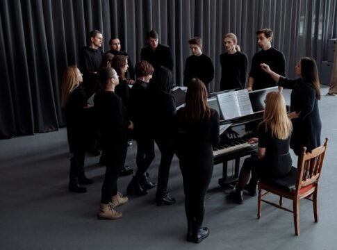 A choir group rehearsing indoors with a conductor and pianist, creating a musical harmony. A choir group rehearsing indoors with a conductor and pianist, creating a musical harmony.