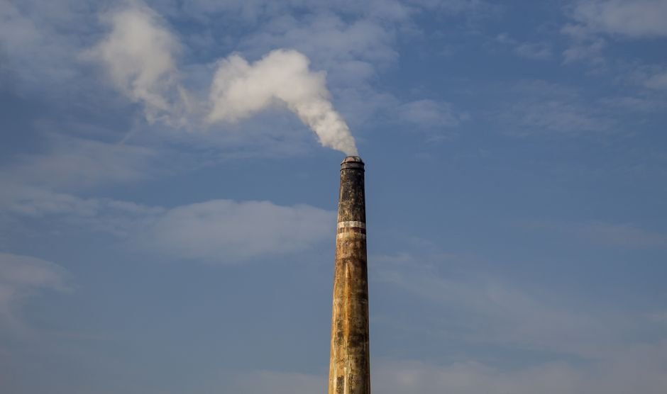 Visakhapatnam Air Quality Declines Sharply in Winter, Data Reveals A factory chimney releasing smoke against a clear blue sky, highlighting air pollution.