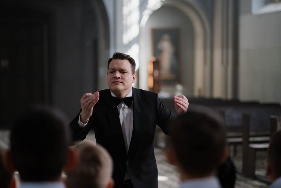 Polish Film ‘What Belongs to Others’ Wins Top Prize at Warsaw Film Festival A male conductor leads a boys' choir rehearsal in a serene church setting.
