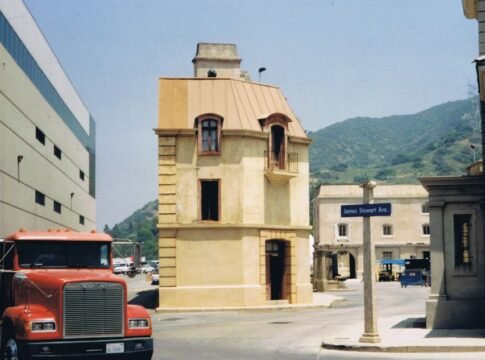 A rustic building on a film studio lot with a parked truck near a mountain background. A rustic building on a film studio lot with a parked truck near a mountain background.