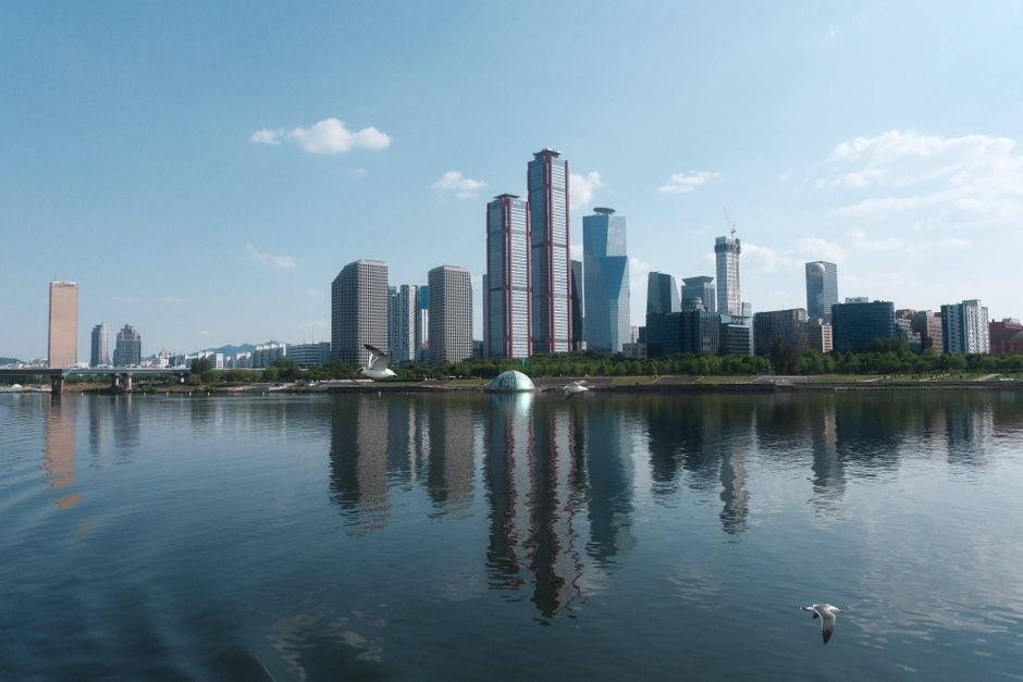 Chinese Landscape Painting Film Series to Expand with Fourth Installment, Director Confirms A stunning Seoul skyline reflecting in the river under a clear blue sky.
