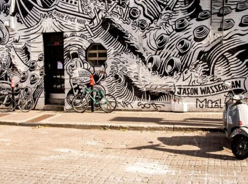 A vibrant black-and-white mural featuring bicycles and a scooter on an urban street. A vibrant black-and-white mural featuring bicycles and a scooter on an urban street.