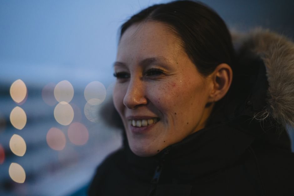 Nyla Innuksuk Explores Narrative Control and Identity in ‘In the Heart of the South’ A woman in Nuuk, Greenland, smiles warmly in a winter coat at twilight.