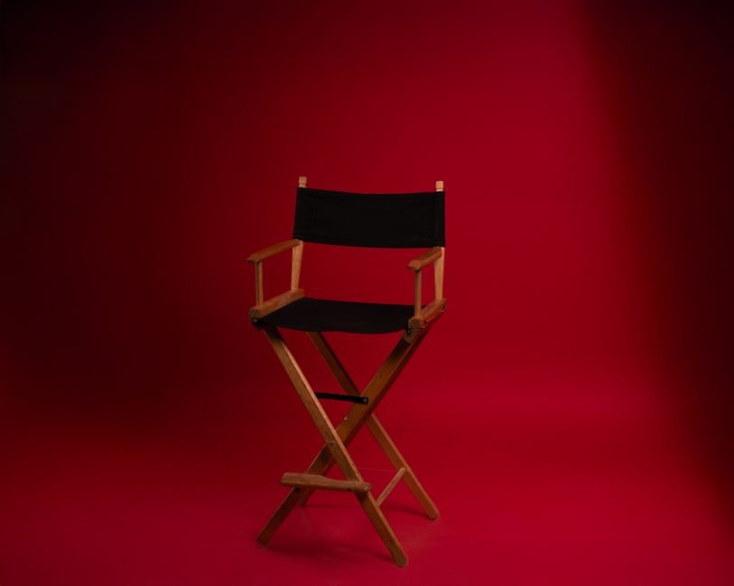 Todd Haynes Discusses Pedro Pascal Project ‘De Noche’ and the Radical Power of Love at Lumière Festival A wooden director's chair against a vibrant red backdrop, symbolizing film industry authority.