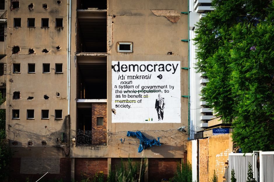ABVP Rally in Lucknow Urges Protection of Democracy An abandoned building features a prominent democracy poster amidst urban decay.