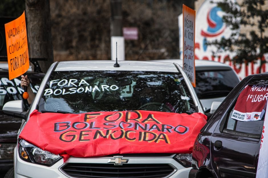 Flávio Bolsonaro Departs Brazil for the U.S. Following Election Loss, Passport Seized Cars displaying anti-Bolsonaro signs during a street protest, highlighting political activism.