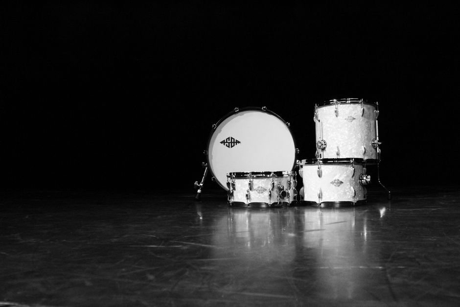 Tom Morello’s Power to the People Festival Unites Music Icons for Democracy Celebration Classic black and white photo of a drum set in a dramatic, moody setting.