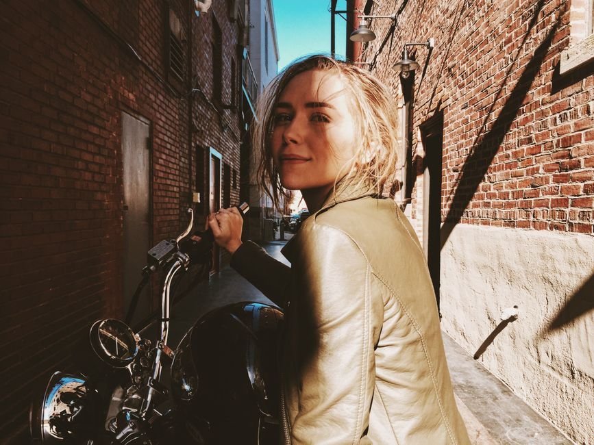 Erin Foster Open to ‘Nobody Wants This’ Season 4, Citing Unfinished Storylines Confident woman in green leather jacket on motorcycle in Atlanta alleyway.