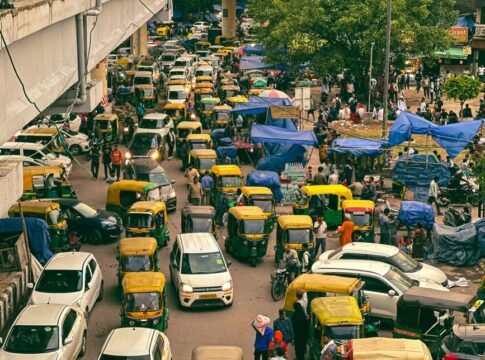 Dynamic aerial view of a busy New Delhi street with auto-rickshaws and pedestrians in a lively market.