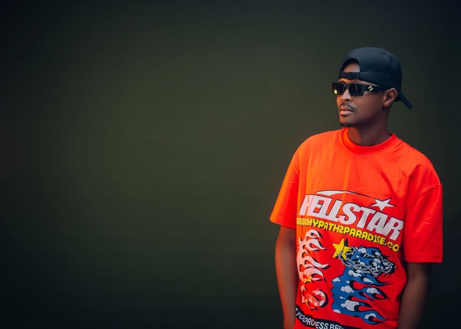 Ne-Yo Details His Polyamorous Relationship With Three Women Fashionable man wearing sunglasses and a bold graphic t-shirt against a solid background.