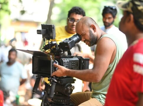Filmmaker using a professional video camera on an outdoor set, surrounded by crew members. Filmmaker using a professional video camera on an outdoor set, surrounded by crew members.