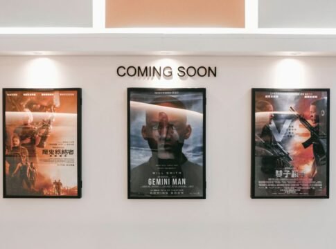 Framed posters of upcoming movies in a cinema hallway under 'Coming Soon' sign. Framed posters of upcoming movies in a cinema hallway under 'Coming Soon' sign.