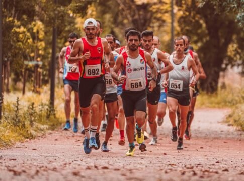 Group of male marathon runners competing on an outdoor trail surrounded by trees.
