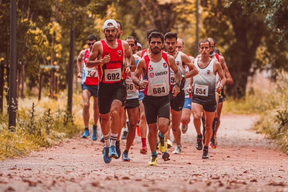Group of male marathon runners competing on an outdoor trail surrounded by trees.