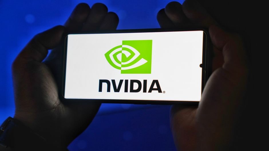 NVIDIA Schedules Q3 Fiscal 2027 Earnings Call for November 17 Hands holding a smartphone showing the NVIDIA logo on a bright screen.