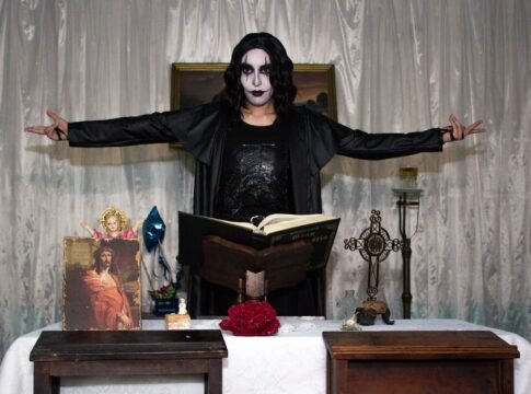 Person in gothic costume performing a dramatic scene indoors with religious symbols. Person in gothic costume performing a dramatic scene indoors with religious symbols.