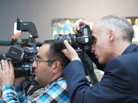 Photographers focusing on event coverage with advanced cameras indoors, showcasing media professionals in action.