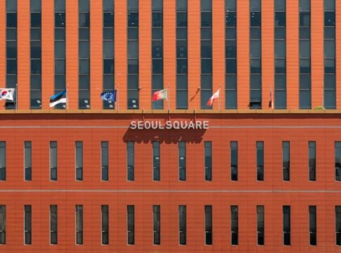 Red facade of Seoul Square with multiple international flags displayed.