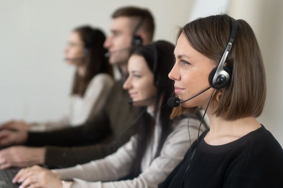 AWS Recognized as a Leader in Gartner’s Contact Center as a Service Magic Quadrant for Fourth Consecutive Year Side view of young coworkers in casual clothes sitting in light workplace with headphones with microphone while surfing on laptop
